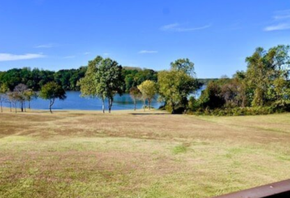 field with trees and water in the distance and a railing in the foreground